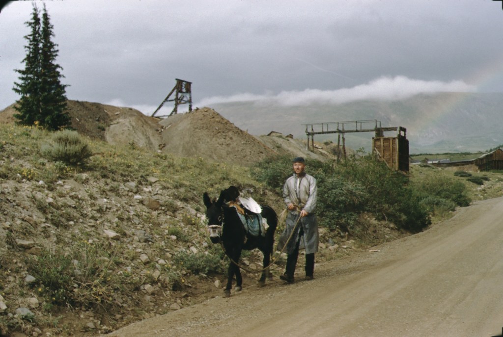 A man with a burro walks from a mine entrance