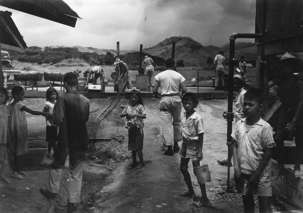 Filipino children play amongst American service personnel after liberation