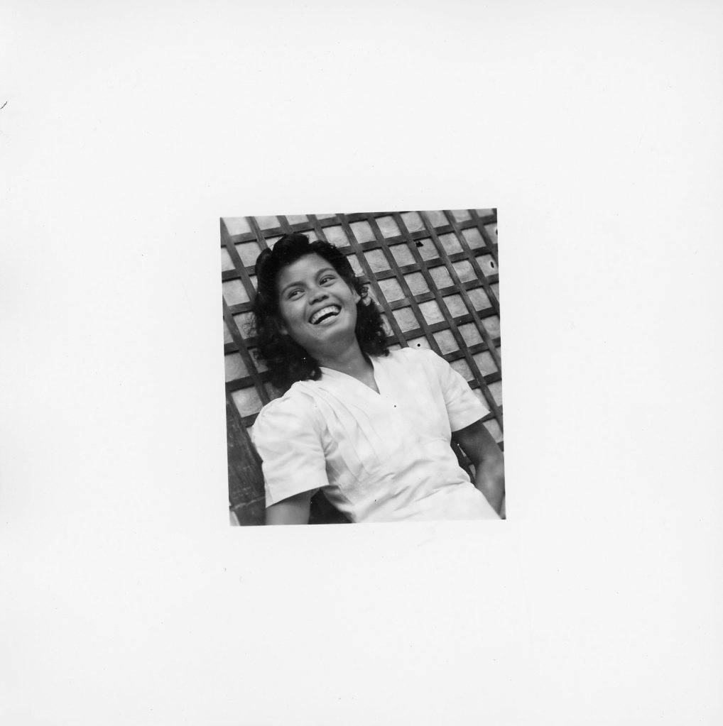 Filipino woman leans against lattice in black and white photo shot by W. R. Allen