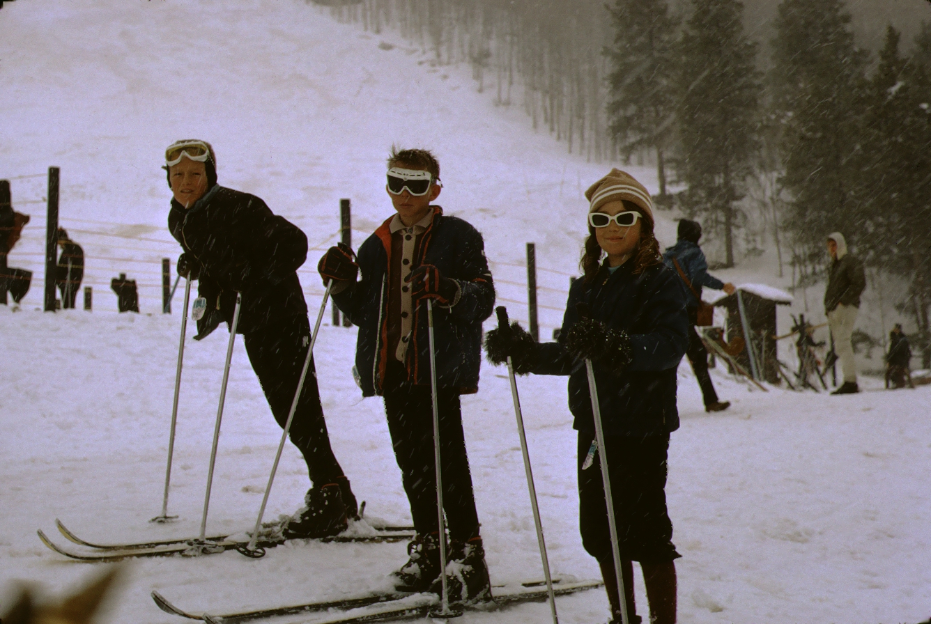 Color photo of Debbie Rutzebeck and unknown males at ski area taken by W. R. Allen